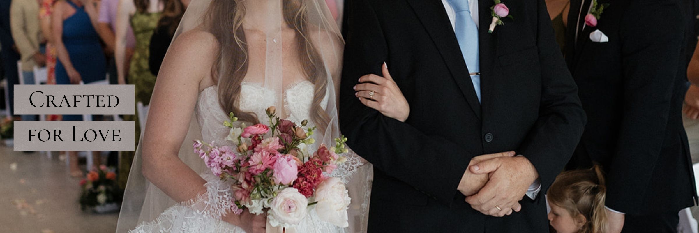 Bride in a long lace veil holding a bouquet while walking down the aisle